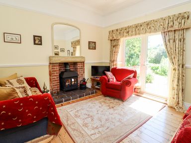 A living room with a fireplace red armchairs and a rug near sliding glass doors at Buzzards Rest in Stannington near Morpeth