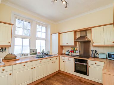 A kitchen with cream cabinets wooden countertops a double window and various kitchen appliances at Buzzards Rest in Stannington near Morpeth