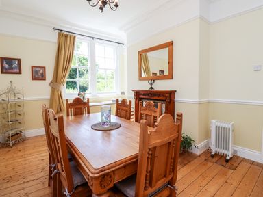 A dining room with wooden table and chairs a window with curtains and a mirror above a fireplace at Buzzards Rest in Stannington near Morpeth