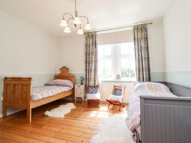 A bedroom with two single beds two chairs and a window with curtains at Buzzards Rest in Stannington near Morpeth