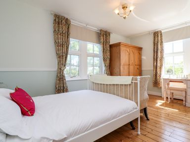 A bedroom with a bed a wooden wardrobe patterned curtains and a dressing table at Buzzards Rest in Stannington near Morpeth