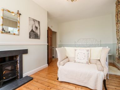 A bedroom with a small couch a bed with a metal headboard a fireplace and a wooden floor at Buzzards Rest in Stannington near Morpeth
