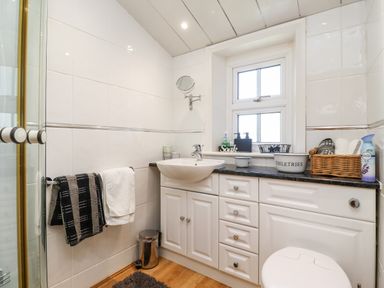 A bathroom with a sink cabinet towels on a rack and toiletries on the counter at Buzzards Rest in Stannington near Morpeth