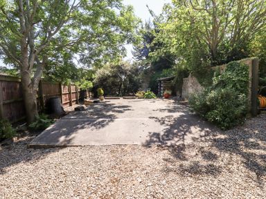 An outdoor area with a gravel ground and a concrete slab surrounded by trees and wooden and stone fences at Buzzards Rest in Stannington near Morpeth