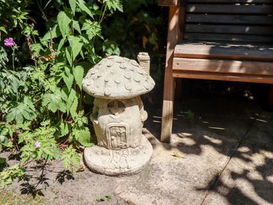 A garden area with a mushroom-shaped stone ornament and part of a wooden bench at Buzzards Rest in Stannington near Morpeth