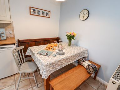 A kitchen dining area with a table covered with a patterned tablecloth and set with croissants glasses and flowers at Pond Farm View in Hinderwell
