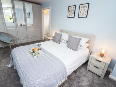 A bedroom with a bed with pillows and a throw blanket a bedside table with a lamp and a built-in wardrobe at Pond Farm View in Hinderwell