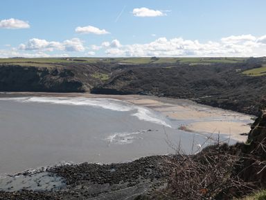 A coastal bay with a sandy beach and rocky shoreline surrounded by hills and fields at Pond Farm View in Hinderwell