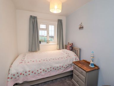 A small bedroom with a single bed next to a window and a wooden bedside table at Pond Farm View in Hinderwell
