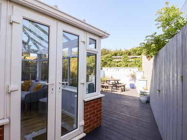 A garden area with wooden decking and a picnic table outside a conservatory at Pond Farm View in Hinderwell