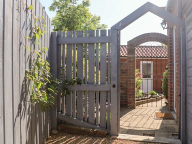 An outdoor area with a wooden gate and a brick archway leading to a garden at Pond Farm View in Hinderwell