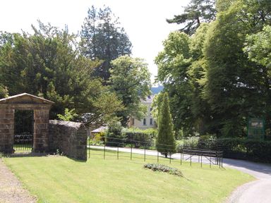 A garden with a stone gate and a path leading to a house surrounded by trees at Dryslwyn Cottage in Llandeilo
