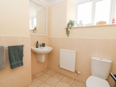 A bathroom with a sink mirror radiator toilet towels and a window with small plants and decor at Dryslwyn Cottage in Llandeilo