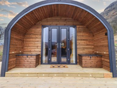 A wooden glamping pod with a wooden deck two storage benches and black framed glass double doors at The Stag - Crossgate Luxury Glamping in Hartsop near Glenridding