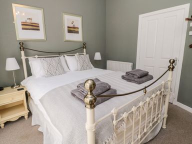 A bedroom with a double bed towels bedside table lamps and two framed pictures on the wall at Kizzie Cottage in Guyzance near Warkworth