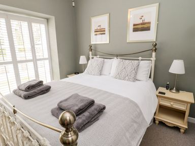 A bedroom with a double bed two bedside tables with lamps and folded towels on the bed at Kizzie Cottage Guyzance near Warkworth