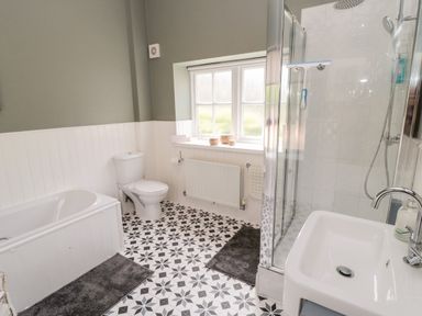 A bathroom with a bathtub toilet shower and sink at Kizzie Cottage in Guyzance near Warkworth