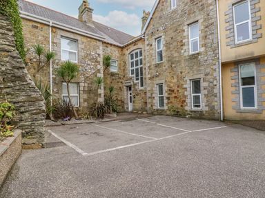 An outdoor parking area with two marked spaces next to a stone building with multiple windows and a door at King Edward's View in Newquay