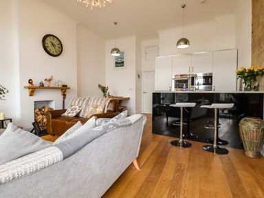 A living room with sofas a kitchen island and wooden floor at King Edward's View in Newquay