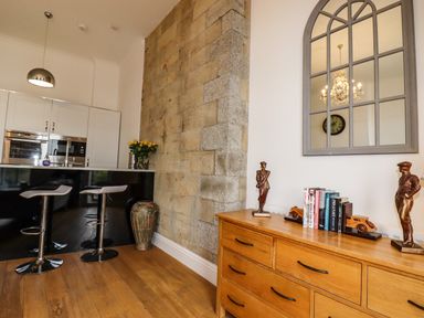 A kitchen area with two bar stools and a wooden dresser with books and statues at King Edward's View in Newquay