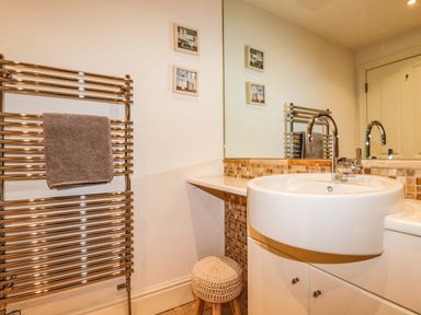 A bathroom with a round sink and a chrome towel rack with a brown towel at King Edward's View in Newquay