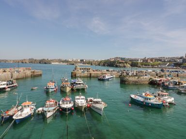 A harbor with fishing boats docked on the water and buildings in the background at King Edward's View in Newquay