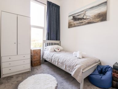 A bedroom with a single bed wardrobe wooden nightstand and bean bag at King Edward's View in Newquay