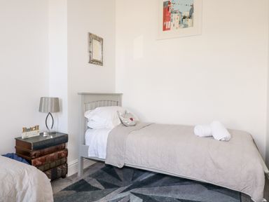 A bedroom with a single bed a nightstand with a lamp and a framed picture on the wall at King Edward's View in Newquay