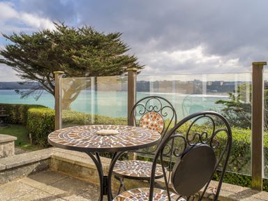 A patio with a mosaic table and two chairs overlooking the ocean with glass railing at King Edward's View in Newquay
