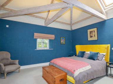 A bedroom with blue walls a yellow bed and wooden chest at The Old Watermill in St Mabyn