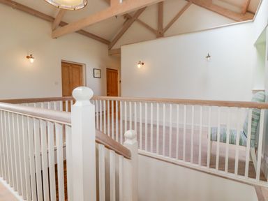 An upstairs landing area with wooden doors a striped chair and exposed ceiling beams at The Old Watermill in St Mabyn