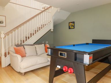 A room with a staircase a two-seater sofa with cushions and a blue pool table at The Old Watermill in St Mabyn