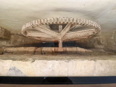 An old rusty gear wheel mounted on a stone wall in a watermill mechanism at The Old Watermill in St Mabyn