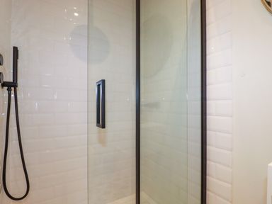 A shower area with glass door and black shower fixtures at The Old Watermill in St Mabyn