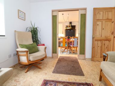 A sitting room with armchairs and a plant looking into a dining room through sliding doors at Yamthwaite in Grizedale near Hawkshead