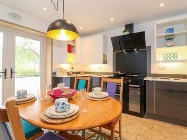 A kitchen with a wooden table set for four people and a black range cooker at Yamthwaite Grizedale near Hawkshead