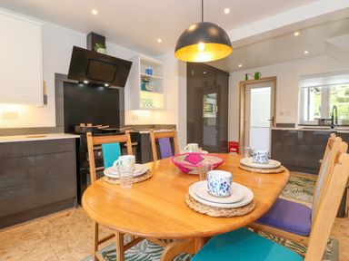 A kitchen with a wooden dining table set with mugs and plates and modern cabinets at Yamthwaite in Grizedale near Hawkshead