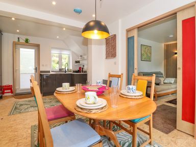 A dining area with a wooden table set for four and a kitchen with dark cabinets in the background at Yamthwaite in Grizedale near Hawkshead