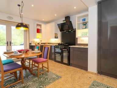A kitchen with dining table and colorful chairs at Yamthwaite in Grizedale near Hawkshead