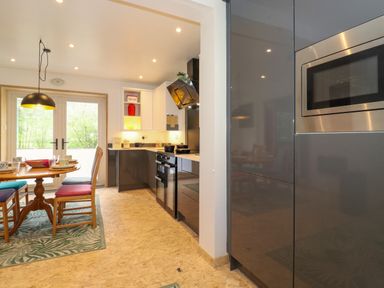 A kitchen with dining table and chairs next to glass doors and built in appliances at Yamthwaite in Grizedale near Hawkshead