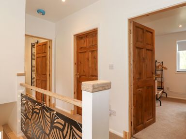 A hallway with wooden doors and a decorative railing with lights at Yamthwaite in Grizedale near Hawkshead