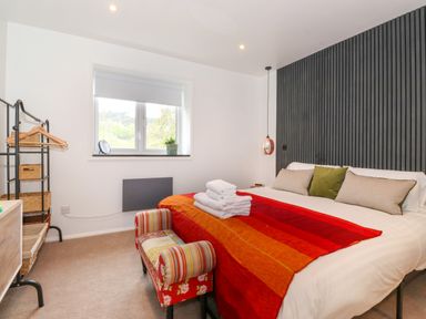 A bedroom with a bed with red and orange blanket and towels on it at Yamthwaite in Grizedale near Hawkshead