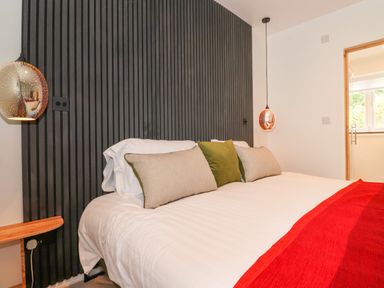A bedroom with a white bedspread green and beige pillows and a red blanket at Yamthwaite in Grizedale near Hawkshead