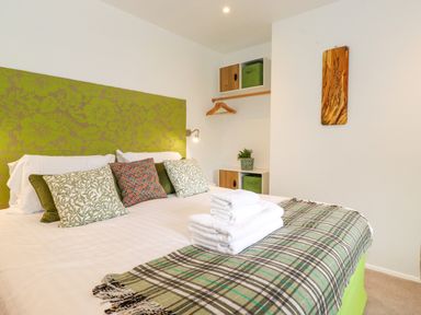 A bedroom with a double bed cushions folded towels and shelving at Yamthwaite in Grizedale near Hawkshead
