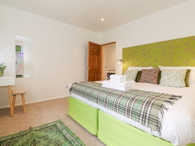 A bedroom with a green headboard bed folded towels and a small vanity table with a mirror at Yamthwaite in Grizedale near Hawkshead
