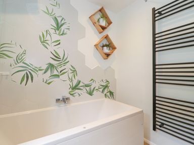 A bathroom with a bathtub decorative hexagonal tiles and two wooden shelves with plants at Yamthwaite Grizedale near Hawkshead
