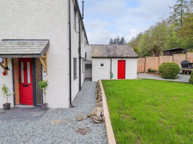 Exterior view of a house with red doors a gravel pathway green grass and garden bushes at Yamthwaite in Grizedale near Hawkshead