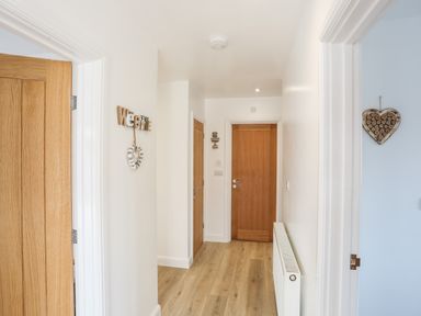 A hallway with wooden doors white walls wooden floor and wall decorations at The Hawthorns in Llanfechell