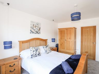 A bedroom with a wooden bed and furniture and blue lampshades at The Hawthorns in Llanfechell