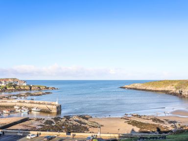 A coastal view with a beach pier boats and rocky shore at The Hawthorns in Llanfechell